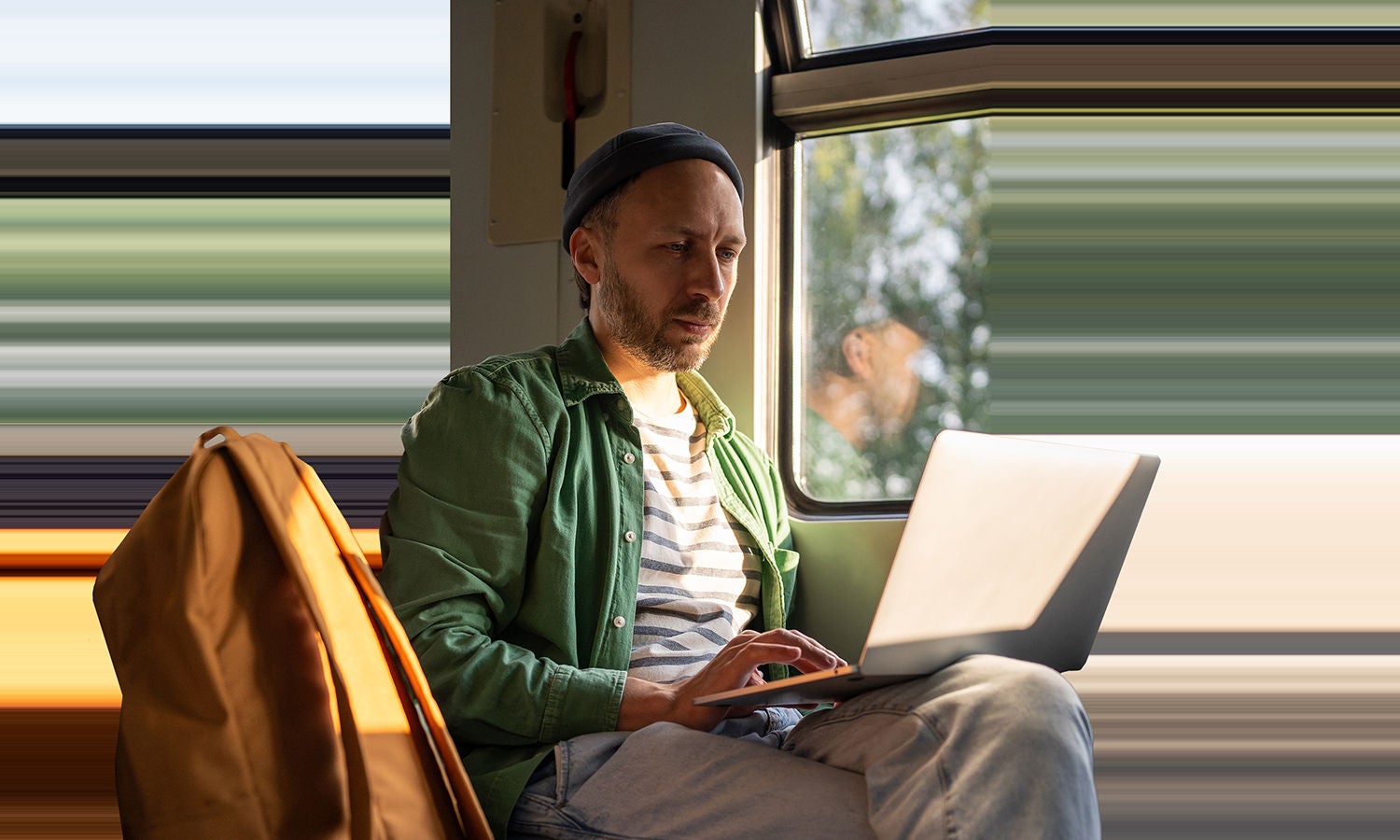Train passenger uses a thin and light pc, the right edge of the pc stretches beyond the frame.